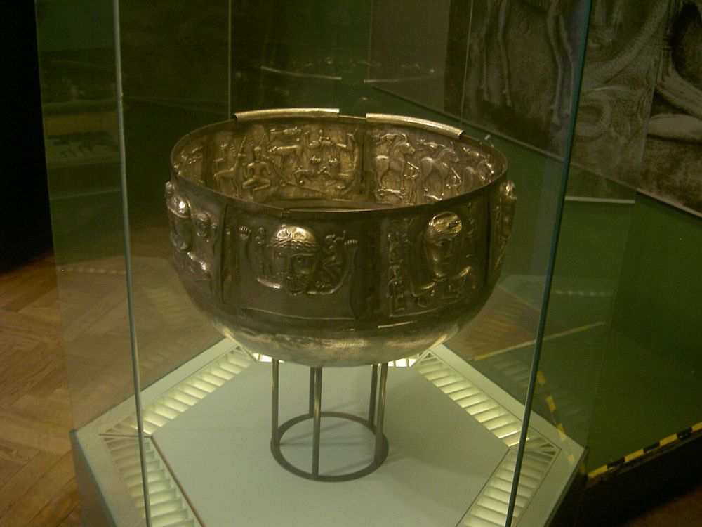 Grand chaudron d'argent orné de visages de divinités et de frises animales, présenté en vitrine de musée