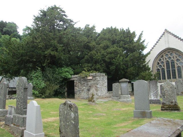 Cimetière écossais avec un if immense derrière un mur d'enclos, église en arrière-plan